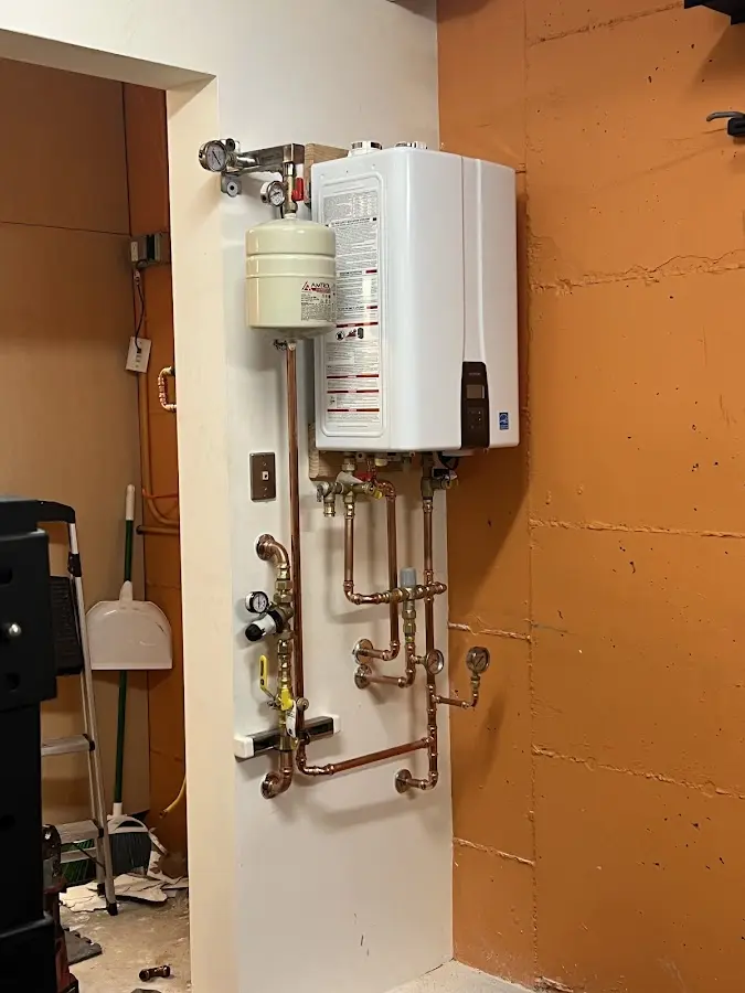 Plumbing technician inspecting water heater connections in Trotwood
